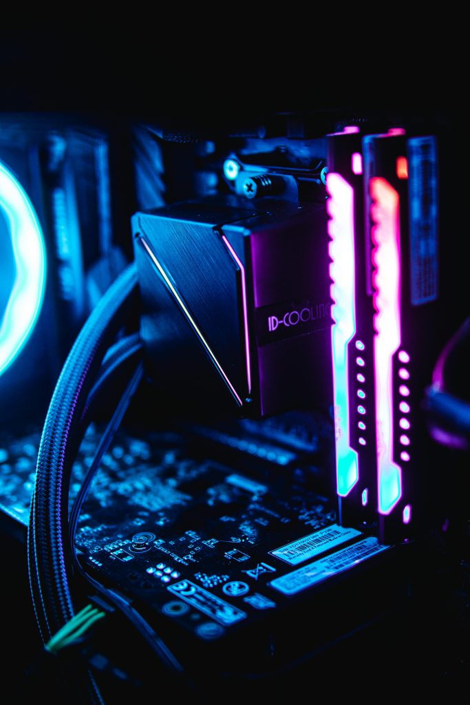 Close-up of RGB-lit PC components showcasing vibrant blue and pink hues in a dark setup.